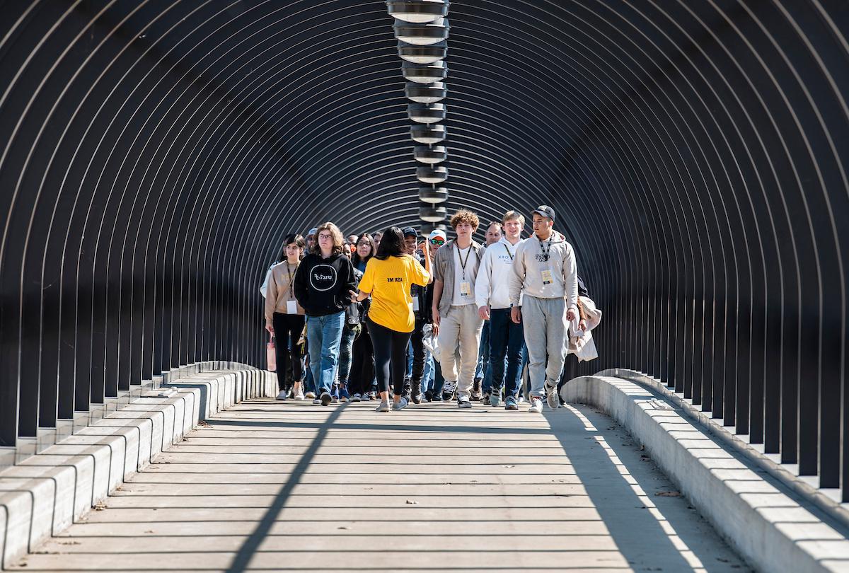 A student worker gives a tour to a large group during a campus visit day.