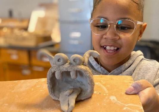 little kid holding clay sculpture.